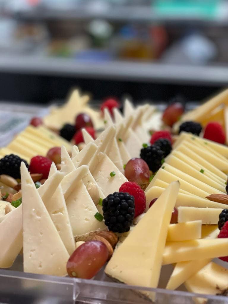 Eine bunte Käseplatte mit Beeren und Nüssen, kunstvoll arrangiert auf einem Tisch.