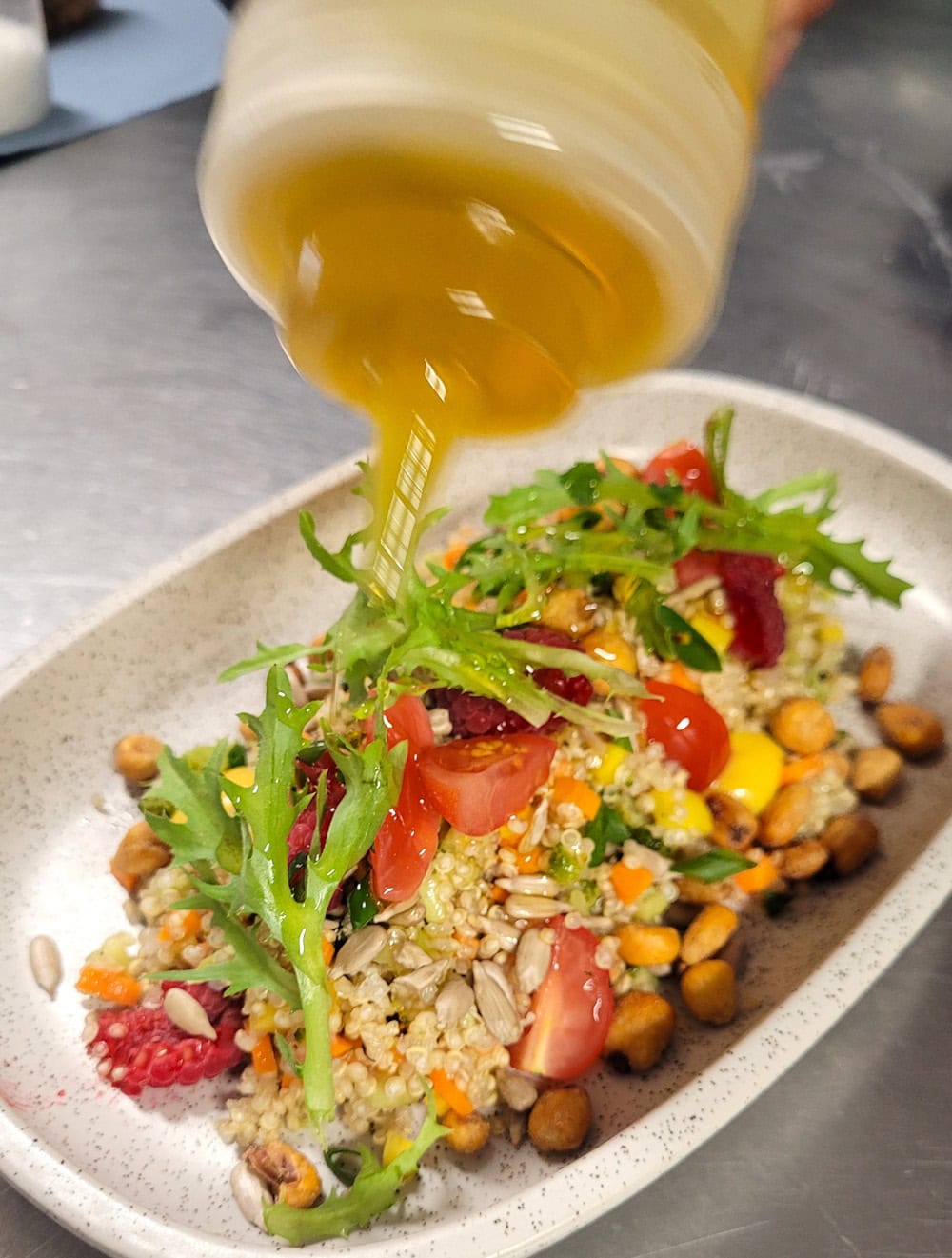 Salat mit Quinoa, Kichererbsen, Tomaten und Kräutern, übergossen mit Öl. Farbig und frisch.