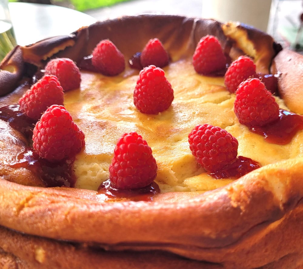 Hausgemachter Käsekuchen mit frischen Himbeeren, goldbraun gebacken.